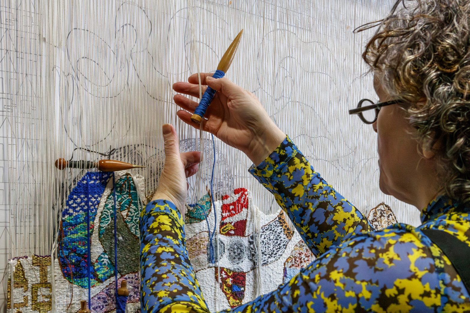 A picture of Lorna Donlon working on a tapestry