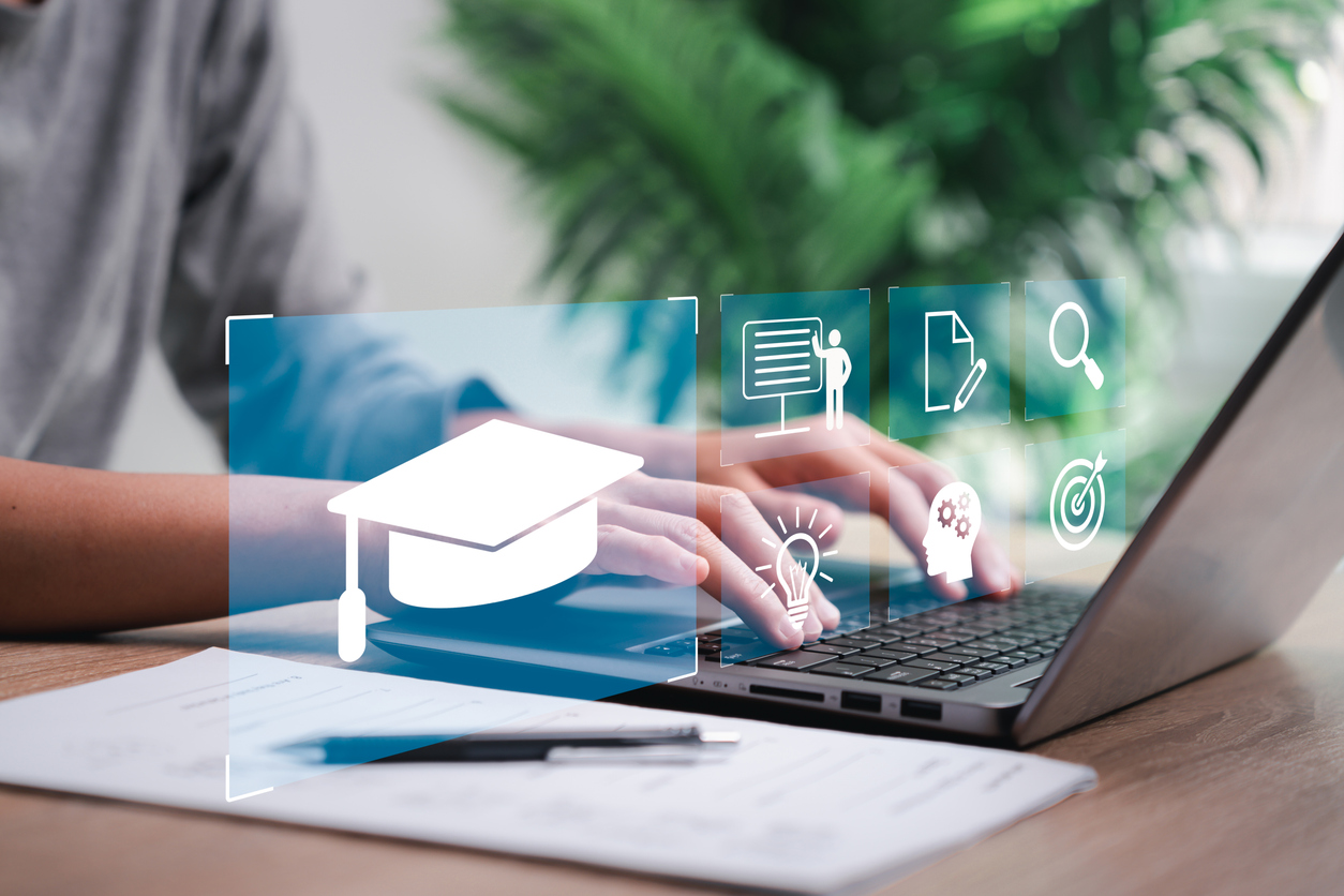 An image of someone working on a laptop with graphics depicting technology and education.